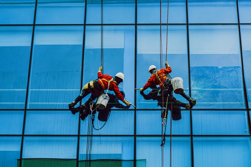 Men Hanging in Ropes Cleaning the Building Glass Windows