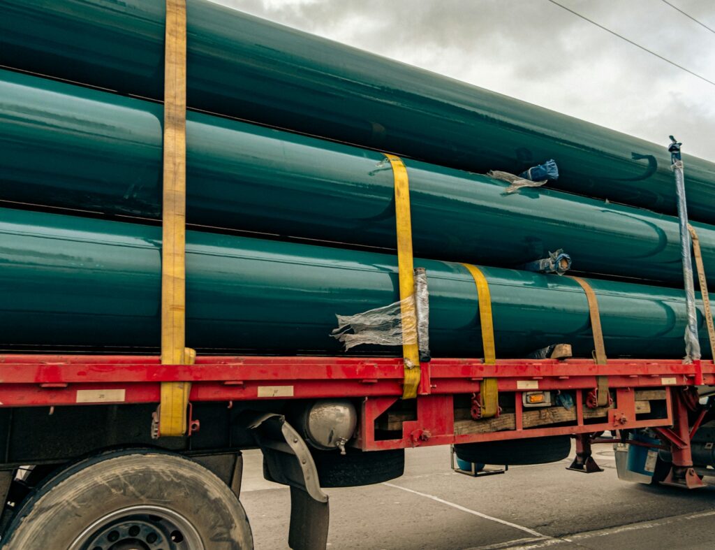 a large truck with a bunch of green pipes on the back of it